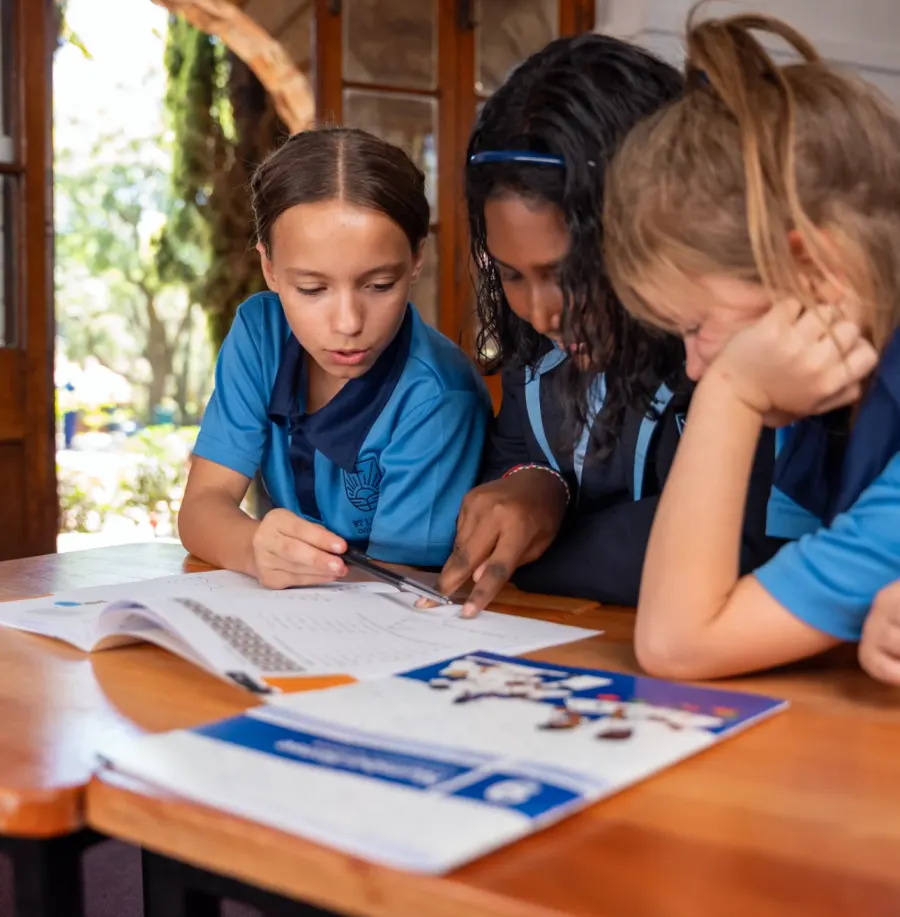 Three children reading a workbook together at a table