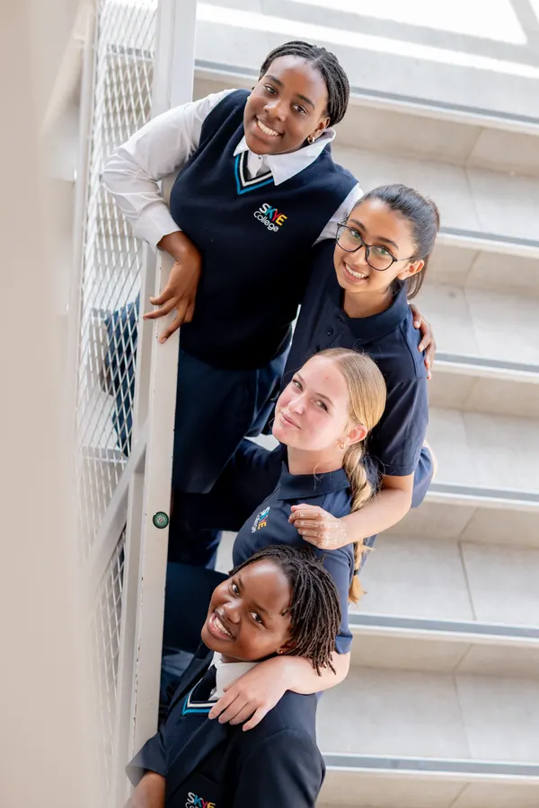 Four Skye College high school students smiling, stacked in a doorway