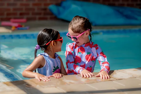 Two girls in sunglasses smiling at the edge of the Skye College pool